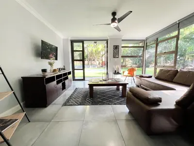 a living room with a couch and a table at Afrique134 Baobab Tree Private Family Garden Suite in Pretoria