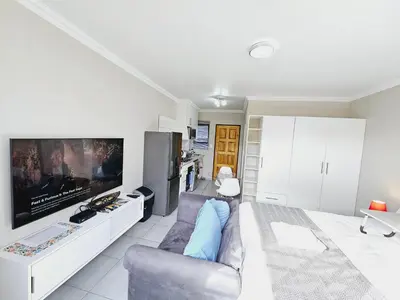 a living room with a couch and a tv at Quantum Heights - Studio Apartment - 2 nights minimum booking in Fourways