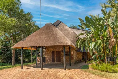 a hut with a thatched roof in a forest at Kruger Park Lodge Unit No. 265 in Hazyview