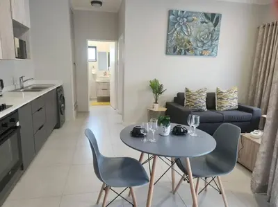 a kitchen and a living room with a table and chairs at 93 on new unique and classy in Midrand