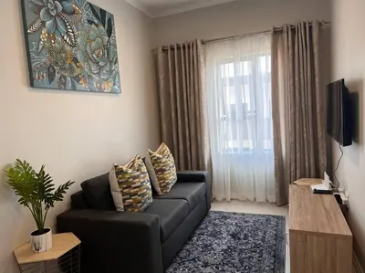 a living room with a black couch and a window at 93 on new unique and classy in Midrand