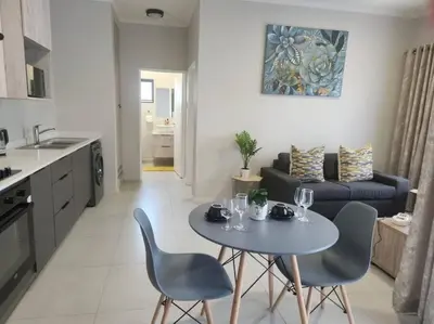 a kitchen and a living room with a table and chairs at 93 on new unique and classy in Midrand