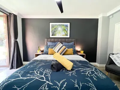 a bedroom with a blue bed with yellow pillows at Afrique134 Willow Tree Private Garden Suite in Pretoria
