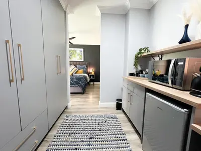 a kitchen with white cabinets and a rug at Afrique134 Willow Tree Private Garden Suite in Pretoria
