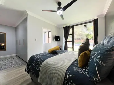 a bedroom with a bed and a ceiling fan at Afrique134 Willow Tree Private Garden Suite in Pretoria