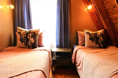 two beds in a room with a window at Serenity Graskop, 3 bedroom A-Frame cottage in Graskop