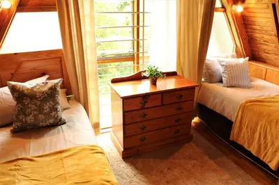 a bedroom with two beds and a dresser and a window at Serenity Graskop, 3 bedroom A-Frame cottage in Graskop