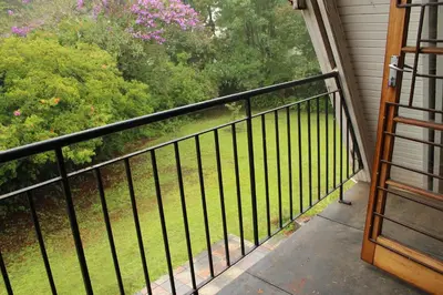 a balcony with a black railing and trees at Serenity Graskop, 3 bedroom A-Frame cottage in Graskop