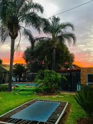 a swimming pool in a yard with two palm trees at Residential Inn in Pretoria