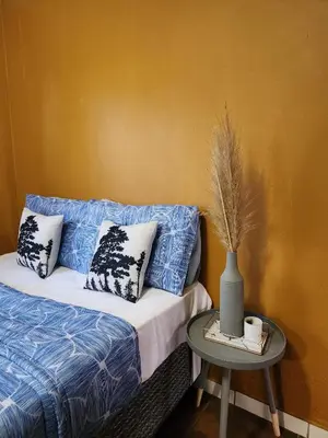 a bed with pillows and a table with a vase on it at Residential Inn in Pretoria