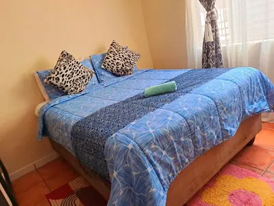 a bed with a blue comforter and pillows on it at Residential Inn in Pretoria