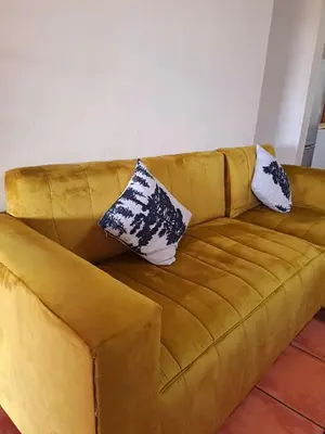 a yellow couch with two pillows on it at Residential Inn in Pretoria