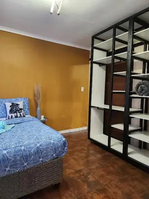 a bedroom with a bed and a book shelf at Residential Inn in Pretoria