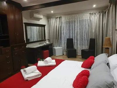 a bedroom with a large white bed with red pillows at Roosthaven Guesthouse in Centurion