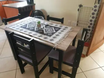 a wooden table with two chairs and a table with a rug on it at Roosthaven Guesthouse in Centurion