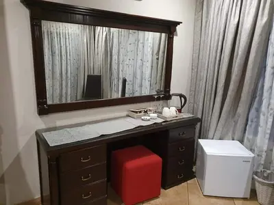 a bathroom with a vanity with a mirror and a red stool at Roosthaven Guesthouse in Centurion
