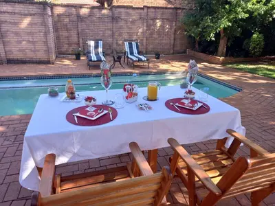 a table with food and drinks on it next to a pool at Roosthaven Guesthouse in Centurion