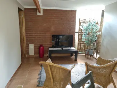 a living room with a tv and a brick wall at Roosthaven Guesthouse in Centurion