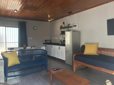 a living room with two blue couches and a kitchen at Blue Lotus Guest House Pta East-Solar power in Pretoria