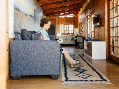 a woman sitting on a couch in a living room at Stone cottage in Haarties in Kalkheuvel
