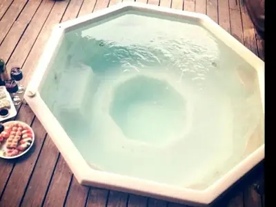 a bath tub filled with water on a wooden deck at Stone cottage in Haarties in Kalkheuvel