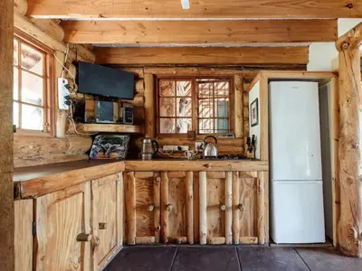a kitchen with wooden cabinets and a white refrigerator at Stone cottage in Haarties in Kalkheuvel
