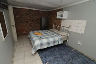 a bedroom with a bed and a brick wall at Quintax Guest House in Pretoria