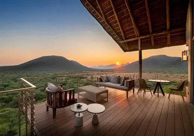 a deck with a sunset in the mountains at Babohi at Qwabi Private Game Reserve by NEWMARK in Bela-Bela