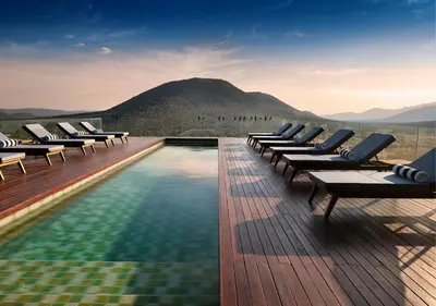 a pool with lounge chairs and a mountain in the background at Babohi at Qwabi Private Game Reserve by NEWMARK in Bela-Bela