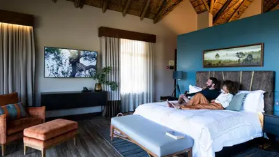 two people sitting on a bed in a hotel room at Babohi at Qwabi Private Game Reserve by NEWMARK in Bela-Bela