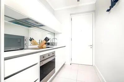 a white kitchen with white cabinets and a tv at Keza Cove at Waterfall Ellipse in Midrand