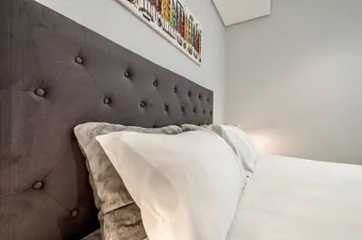 a bed with a brown padded headboard and a pillow at Keza Cove at Waterfall Ellipse in Midrand