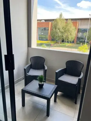 two chairs and a table with a potted plant on a balcony at Blue Lilly - 50 on Lever Unit 19 in Midrand